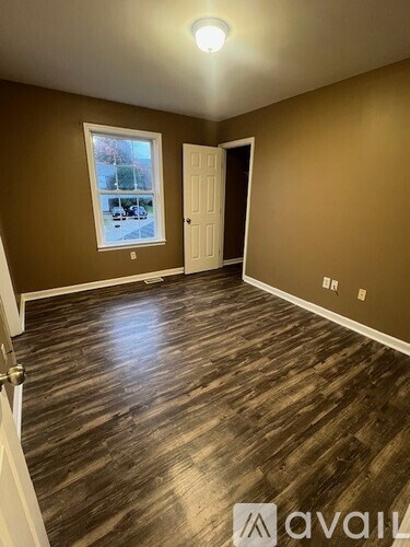 A room with wooden flooring and a window showing an outdoor scene.