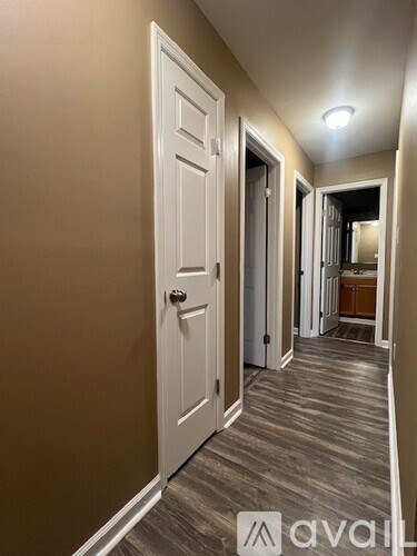 A hallway with a white door and a mirror on the wall.