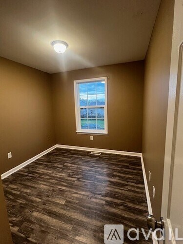 A room with a window and wooden flooring.