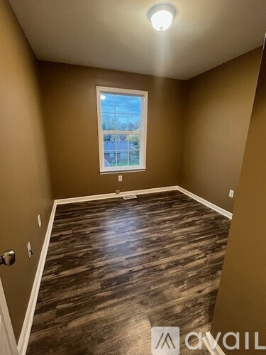 A room with a window and wooden flooring.