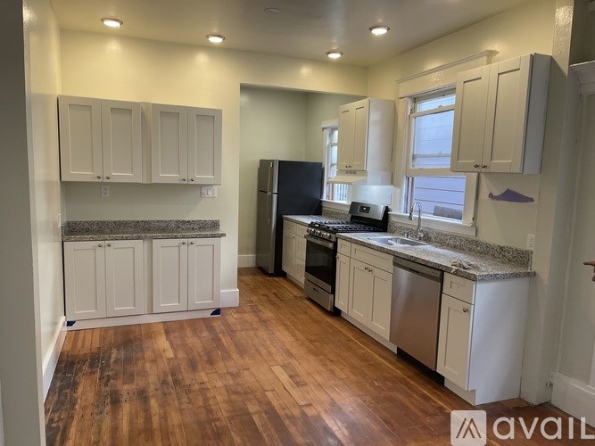 A kitchen with white cabinets and a wooden floor.
