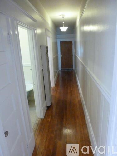 A hallway with white walls and wood floors.