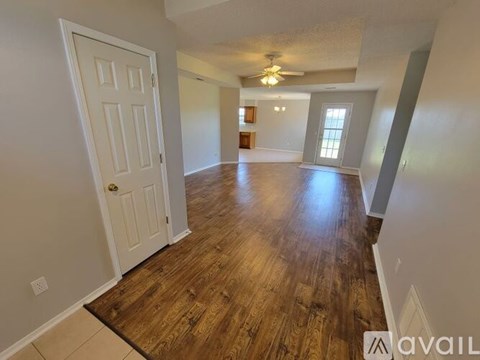 A spacious room with wooden floors and a ceiling fan.