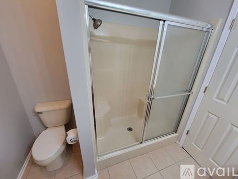 A white toilet sits next to a walk-in shower.