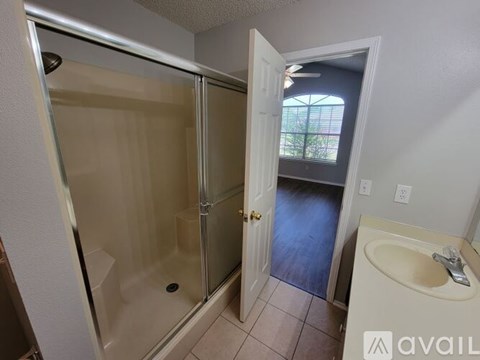 A bathroom with a glass shower door and a sink.
