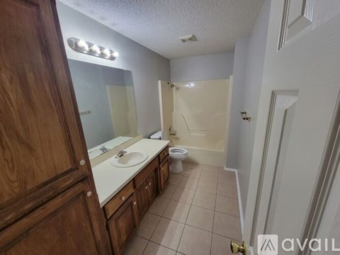 A bathroom with a sink, mirror, toilet, and a shower.
