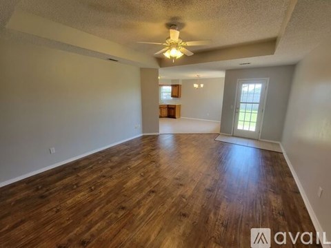 A spacious room with wooden floors and a ceiling fan.