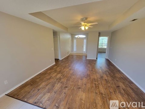 A spacious room with wooden flooring and a ceiling fan.