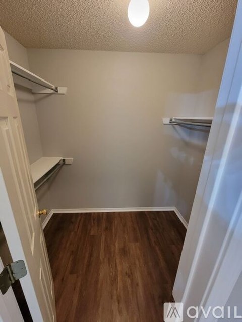 A small, empty room with wood flooring and white walls.