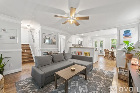 A living room with a grey couch and a ceiling fan.