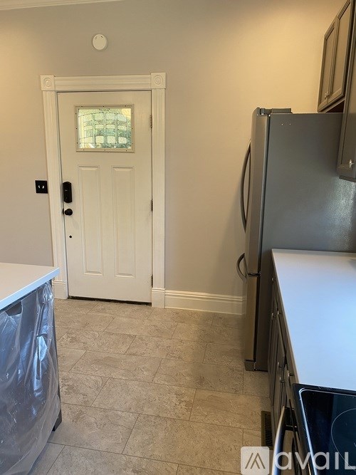 A kitchen with a white door and a fridge.