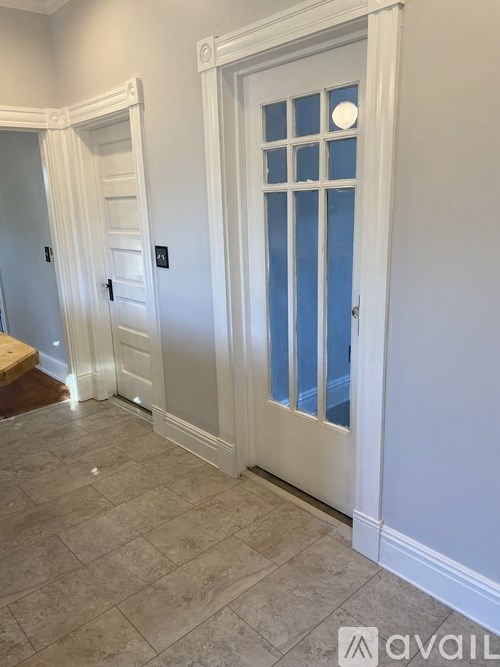 A white door with a glass panel is in a room with a tiled floor.