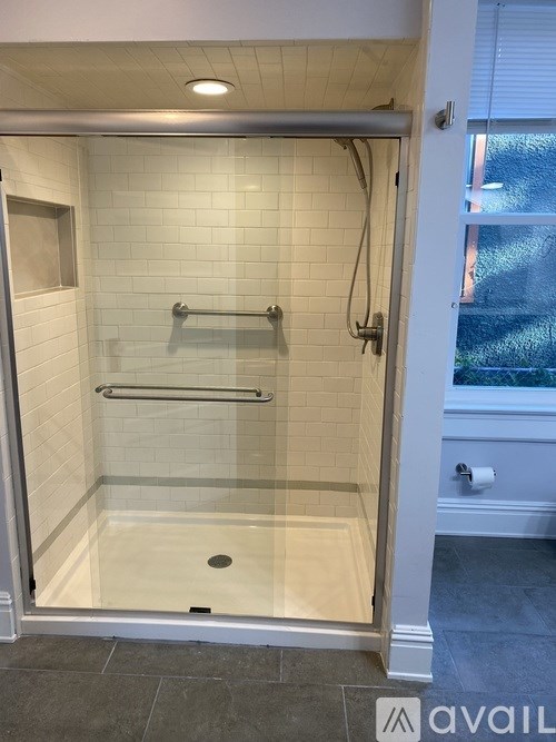 A glass shower stall with a silver handle and a glass door.