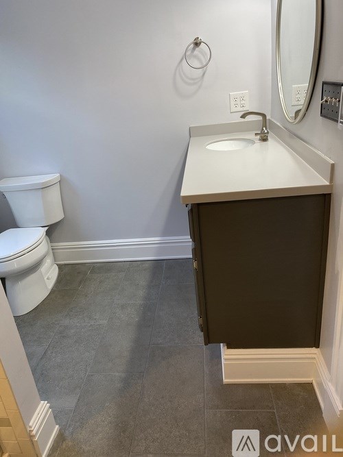 A bathroom with a toilet, sink, and mirror.