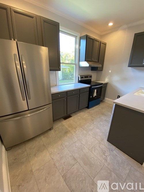 A kitchen with a stainless steel refrigerator and cabinets.