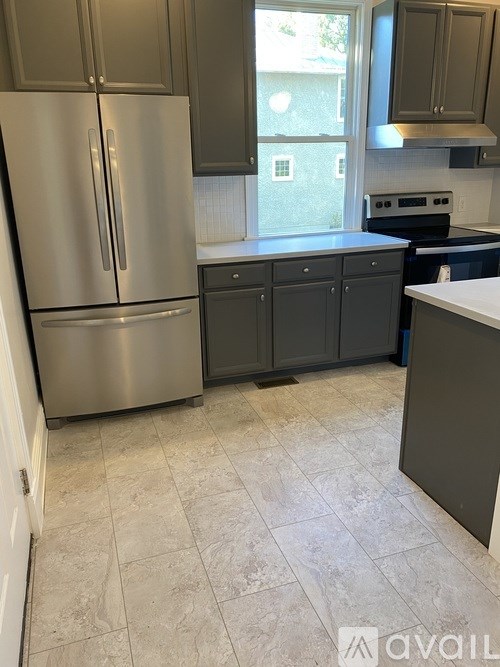 A kitchen with a stainless steel refrigerator and cabinets.
