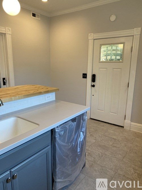 A kitchen with a white counter top and a white door.