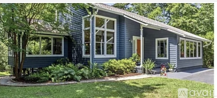 A blue house with white windows and a red door.