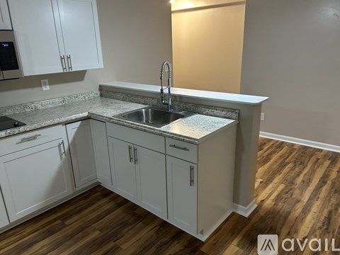 A kitchen with white cabinets and a wooden floor.