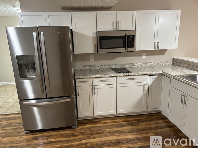 A kitchen with a stainless steel refrigerator and white cabinets.