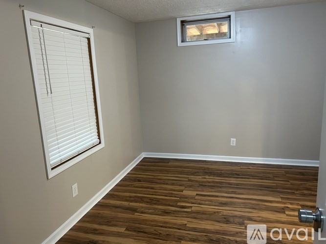A room with wooden flooring and a window with blinds.