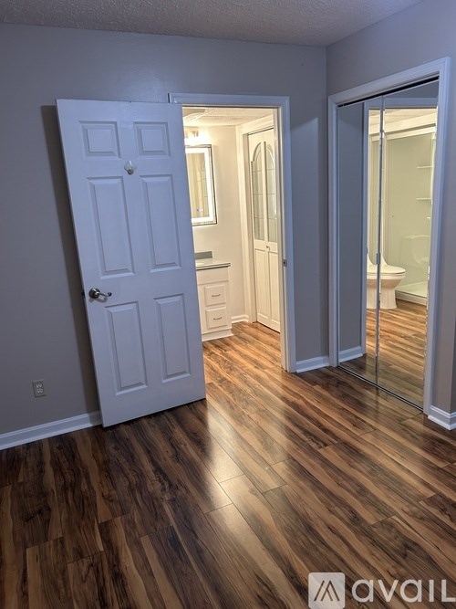 A room with a white door and wooden flooring.