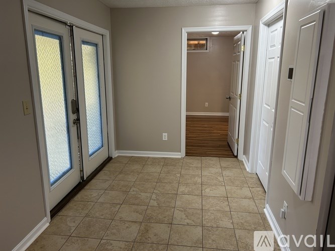 A hallway with a tiled floor and white walls.