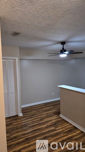 A room with a ceiling fan and wooden flooring.