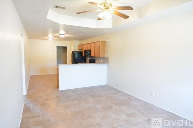 A room with a ceiling fan and a kitchenette.