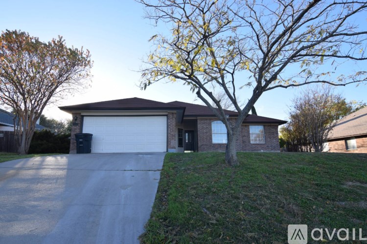 A house with a driveway and a tree in front of it.