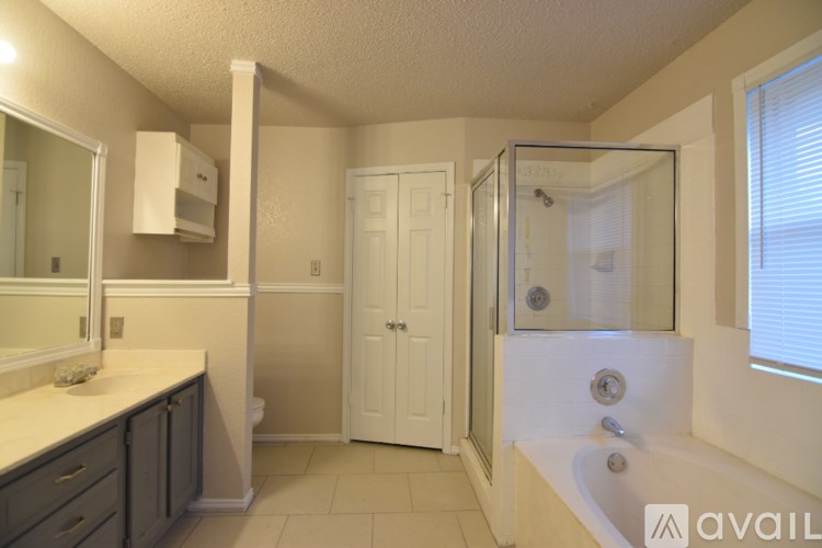 A bathroom with a sink, mirror, and shower.