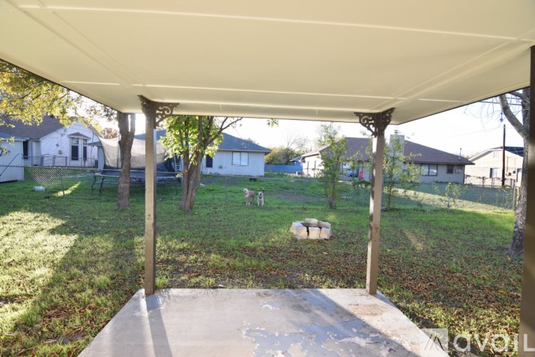 A patio with a white canopy and a concrete slab in the foreground.