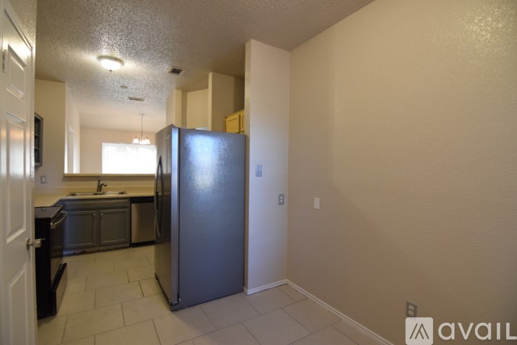 A kitchen with a refrigerator, sink, and cabinets.