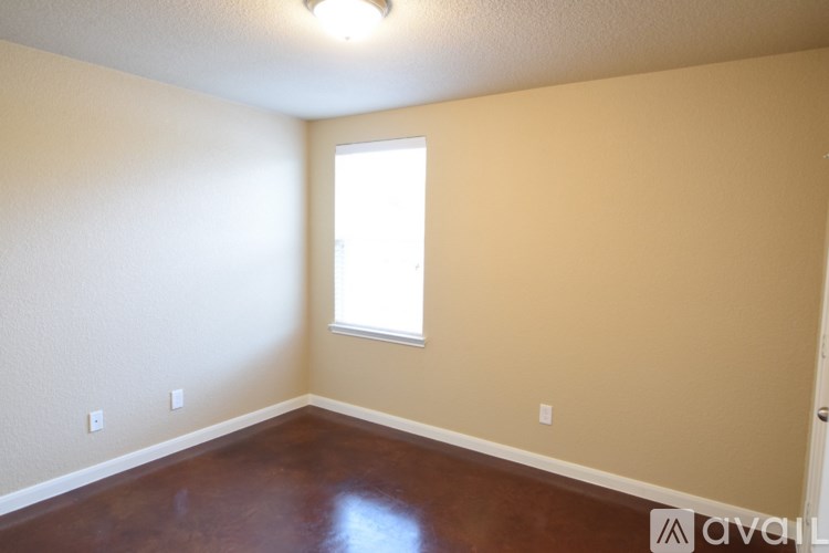 A room with a brown floor and a window letting in light.
