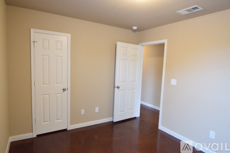 A room with two white doors and a brown floor.