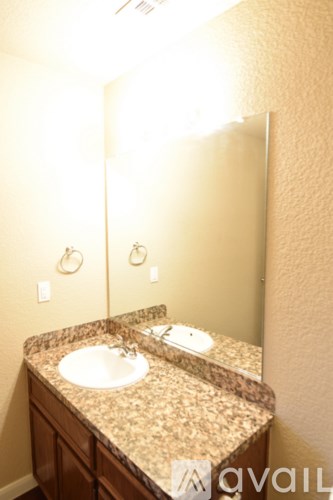 A bathroom sink with a granite countertop and a mirror above it.