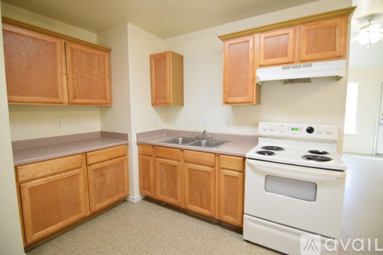 A kitchen with wooden cabinets and a white stove top oven.