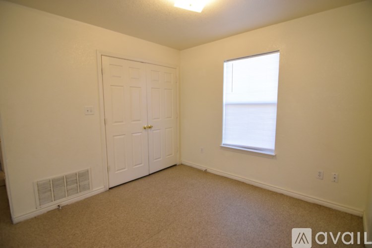 A room with a carpeted floor, a door, and a window.