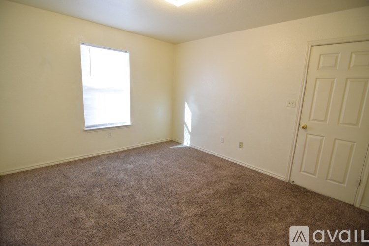 A room with a carpeted floor, a window, and a door.