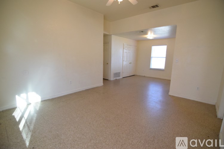 A large empty room with a carpeted floor and a window.