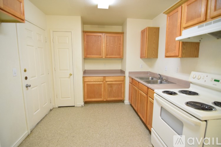 A kitchen with white appliances and wooden cabinets.