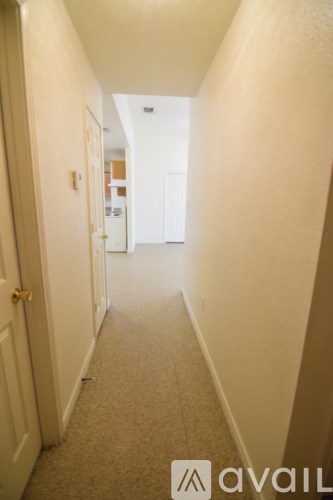 A hallway with a carpeted floor and white walls.