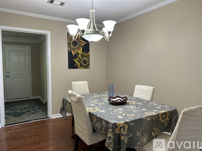 A dining room with a floral tablecloth and chairs.