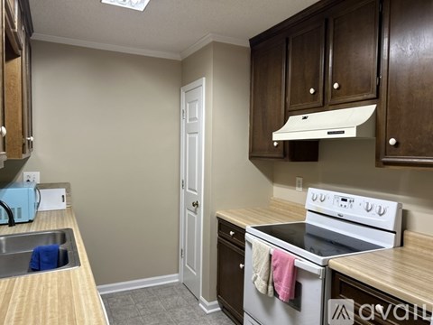 A kitchen with a white stove and wooden cabinets.