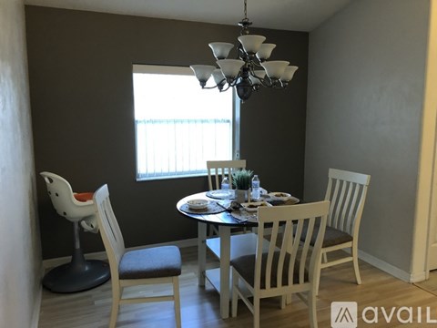 A dining room with a table set for two and a chandelier hanging from the ceiling.
