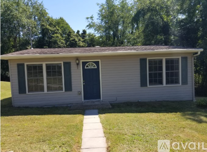 A small house with a blue door and dark green shutters.