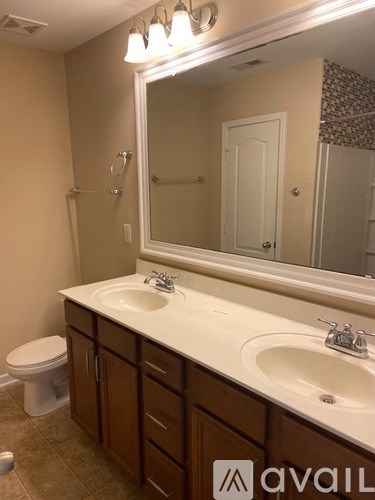 A bathroom with a toilet, sink, and mirror.