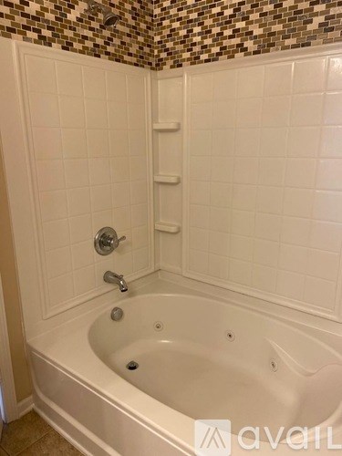 A white bathtub with a shower head and faucet.