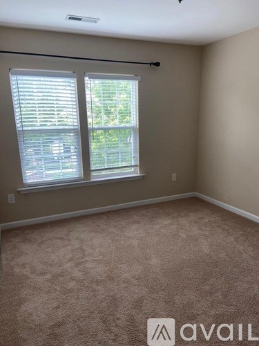 A room with a carpeted floor and a window with blinds.