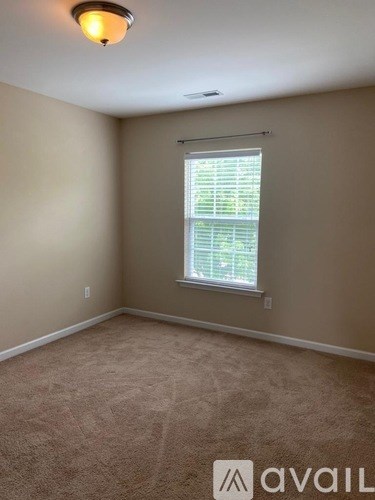 A room with a carpeted floor and a window with blinds.